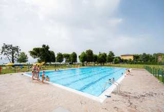 Außenpool mit Badegästen, umgeben von Rasenflächen im Campeggio del Garda, Veneto, Italien.