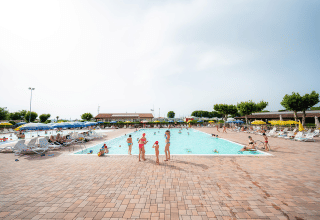 Børnefamilier nyder en solrig dag ved svømmebassinet på Campeggio del Garda feriepark i Veneto, Italien.
