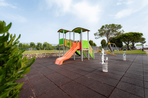 Area giochi con scivolo, altalene e giochi a molla a Campeggio del Garda, Veneto, Italia, all’aperto nel verde.