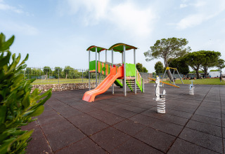Aire de jeux avec toboggan et balançoires à Campeggio del Garda, Veneto, Italie, entourée de verdure et arbres.
