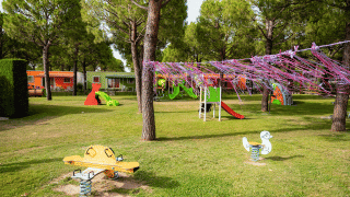 Parque infantil en Campeggio del Garda con toboganes, columpios y bungalows coloridos en Veneto, Italia.