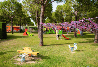 Playground at Campeggio del Garda featuring slides, swings and colorful cabins among trees in Veneto, Italy.