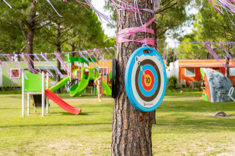 Parque infantil con tobogán, muro de escalada y diana en un árbol en Campeggio del Garda, Véneto, Italia.