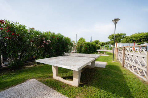Table de ping-pong extérieure entourée de verdure au Campeggio del Garda, parc de vacances en Vénétie, Italie.