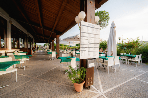Gemütlicher Außenbereich eines Restaurants im Campeggio del Garda, Veneto, Italien, mit grünen Tischdecken.