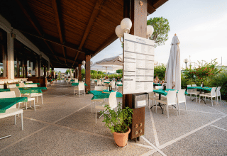 Udendørs restaurantområde på Campeggio del Garda i Veneto, Italien, med grønne duge og afslappet atmosfære.