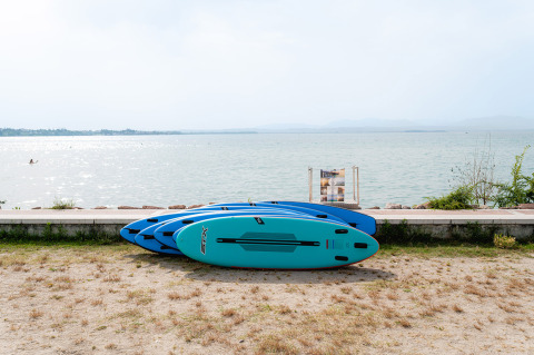 Cuatro tablas de paddle surf azules en la orilla de un lago en Campeggio del Garda, Veneto, Italia.