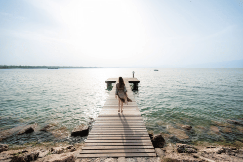Donna che cammina su un molo di legno a Campeggio del Garda, Veneto, Italia, in una giornata di sole.