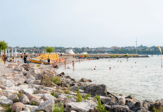 Plage au Campeggio del Garda, Vénétie, Italie, avec baigneurs, rochers et ambiance estivale.