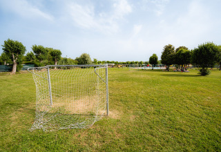 But de football sur pelouse au Campeggio del Garda, parc de vacances en Vénétie, Italie, entouré d’arbres.