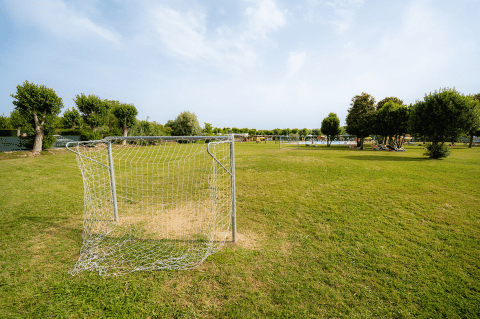 Fußballtor auf einer grünen Wiese im Campeggio del Garda Ferienpark in Venetien, Italien, mit Bäumen.