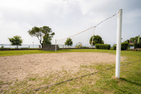 Sand-Volleyballfeld im Campeggio del Garda in Venetien, Italien, mit grünem Rasen und Netz.