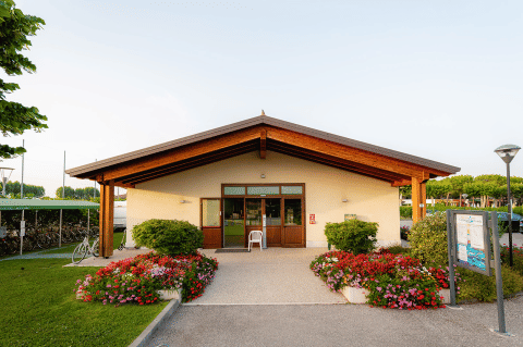Front view of Campeggio del Garda’s main building with flower beds and greenery in Veneto, Italy.