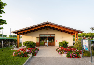 Front view of Campeggio del Garda’s main building with flower beds and greenery in Veneto, Italy.