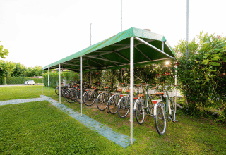 Cykelparkering med grøn overdækning og udlejningscykler i Campeggio del Garda, Veneto, Italien.