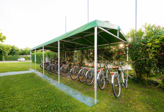 Aparcamiento de bicicletas con alquileres bajo techo verde en Campeggio del Garda, Véneto, Italia.