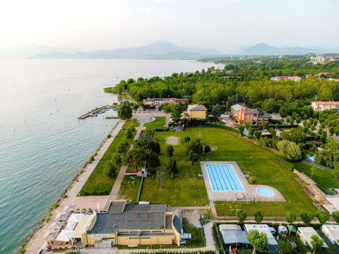 Vista aérea del parque de vacaciones Campeggio del Garda en Véneto, Italia, con piscina, lago y áreas verdes.