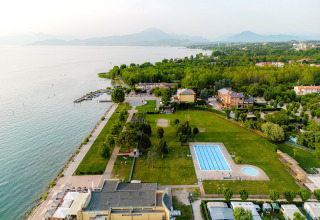Vista aérea del parque de vacaciones Campeggio del Garda en Véneto, Italia, con piscina, lago y áreas verdes.