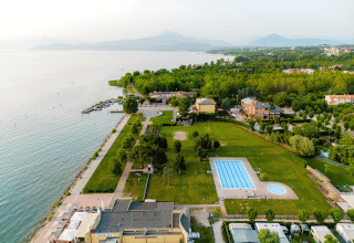 Vue aérienne du parc de vacances Campeggio del Garda en Vénétie, Italie, avec piscine, lac et espaces verts.