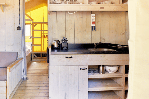 Kitchen area inside a safari tent at Villatent Outback, Campeggio del Garda, Italy, with wood decor.