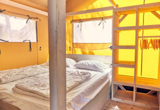Interieur van een Villatent Outback safaritent op Campeggio del Garda in Italië met bed en open kast.