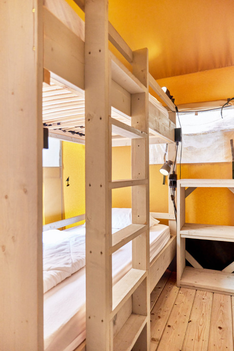 Interieur van een safaritent met stapelbedden en houten meubels bij Villatent Outback, Campeggio del Garda.