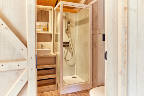 Baño moderno con ducha y lavamanos en tienda safari en Campeggio del Garda, Italia, con detalles en madera.