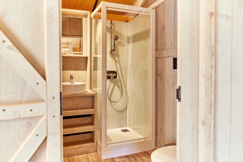 Modern bathroom with shower and sink in a safari tent at Campeggio del Garda, Italy, with wood accents.