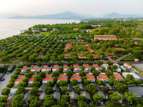Aerial view of Villatent Outback safari tents at Campeggio del Garda, Italy, near a scenic lakeshore.