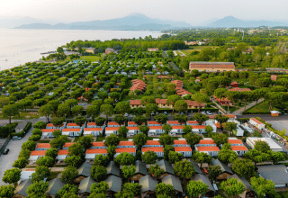 Aerial view of Villatent Outback safari tents at Campeggio del Garda, Italy, near a scenic lakeshore.