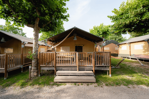 Safaritent Villatent Outback op Campeggio del Garda in Italië met houten veranda en groene bomen.