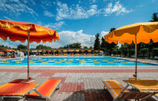 Udendørs swimmingpool med farverige liggestole og parasoller på Campeggio Gasparina, Veneto, Italien.