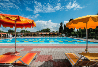 Buitenzwembad met kleurrijke ligstoelen en parasols op Campeggio Gasparina, Veneto, Italië.
