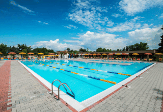 Outdoor swimming pool with lanes, sunbeds, and yellow umbrellas at Campeggio Gasparina, Veneto, Italy.