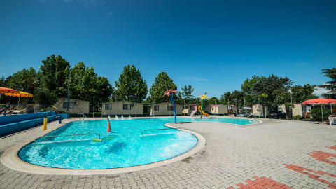 Zwembad en chalets bij Campeggio Gasparina vakantiepark in Veneto, Italië, tijdens een zonnige dag.