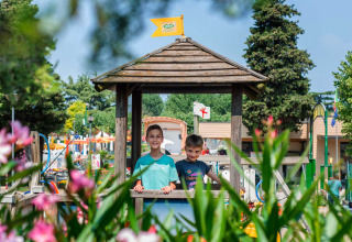Twee kinderen spelen bij een houten prieel in Campeggio Gasparina, een vakantiepark in Veneto, Italië, met bloemen.