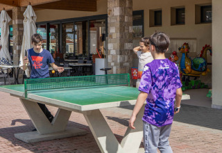 Kinderen spelen buiten pingpong op Campeggio Gasparina, een vakantiepark in Veneto, Italië.