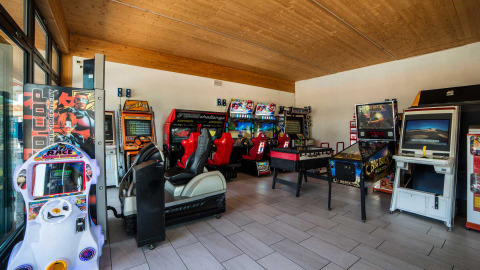 Spielhalle im Campeggio Gasparina in Venetien, Italien, mit Arcade-Automaten, Flipper und Tischfußball.
