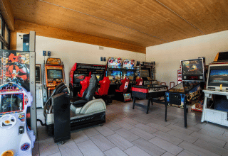 Spielhalle im Campeggio Gasparina in Venetien, Italien, mit Arcade-Automaten, Flipper und Tischfußball.