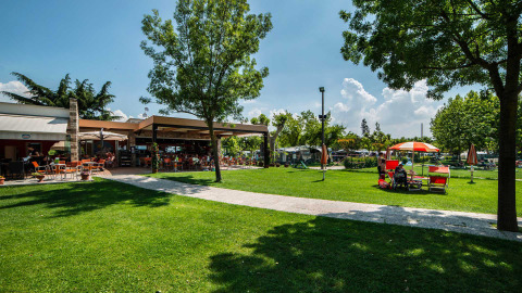 Outdoor seating area and green lawns at Campeggio Gasparina holiday park in Veneto, Italy on a sunny day.