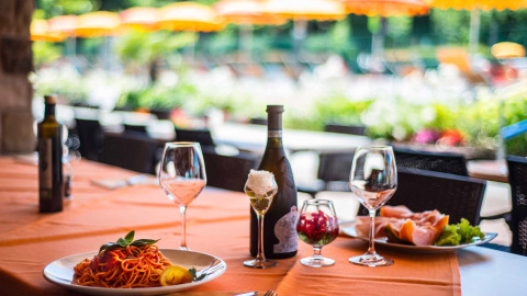 Mesa servida con vino, pasta y jamón en Campeggio Gasparina, un parque vacacional en Véneto, Italia.