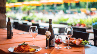 Mesa servida con vino, pasta y jamón en Campeggio Gasparina, un parque vacacional en Véneto, Italia.
