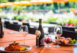 Mesa servida con vino, pasta y jamón en Campeggio Gasparina, un parque vacacional en Véneto, Italia.