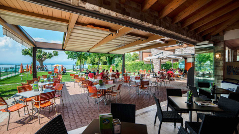 Zona de comedor al aire libre en Campeggio Gasparina, un parque vacacional en Véneto, Italia, con vista al lago.