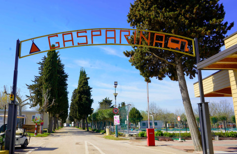 Puerta de entrada al parque vacacional Campeggio Gasparina en Véneto, Italia, rodeada de árboles y servicios.