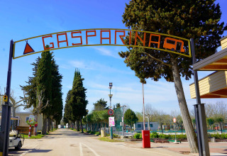 Toegangspoort van vakantiepark Campeggio Gasparina in Veneto, Italië, omringd door bomen en voorzieningen.