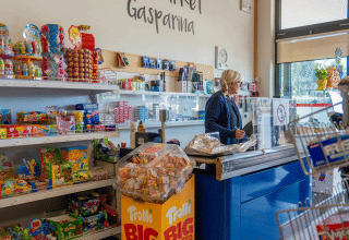 Intérieur d’une boutique du Campeggio Gasparina, Vénétie, Italie, avec rayons de bonbons et une caissière.