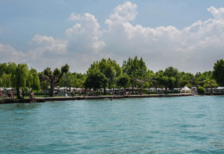 Uitzicht op het meer bij Campeggio Gasparina in Veneto, Italië, met bomen en tenten langs de waterkant.