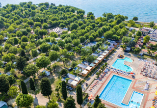 Vista aerea di Campeggio Gasparina in Veneto, Italia, con piscine, bungalow e tante aree verdi vicino al lago.