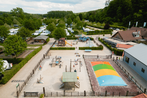 Vista aerea del Camping 't Geuldal, parco vacanze in Limburgo, Paesi Bassi, con parco giochi e campeggiatori.